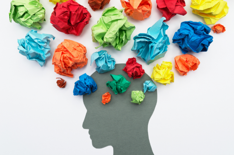 Colorful crumpled paper balls representing emotions above a silhouette of a head, symbolizing the emotional experiences of family caregivers in Alzheimer's care.