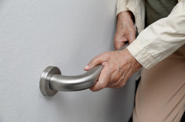 Senior hand gripping a metal grab bar, emphasizing home safety for seniors and support in mobility.