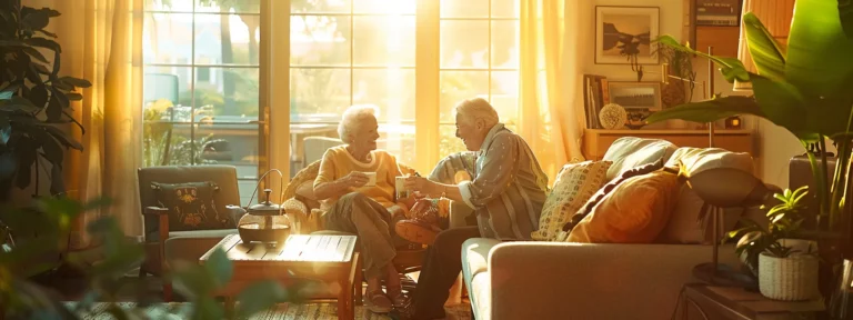 Elderly couple enjoying companionship in a warm, sunlit living room, surrounded by plants and cozy furnishings, highlighting the importance of personal connections in senior care.