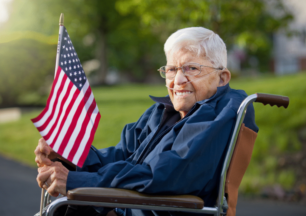 Elderly veteran in wheelchair smiling and holding a small American flag, symbolizing pride and rights in VA-approved home care services.