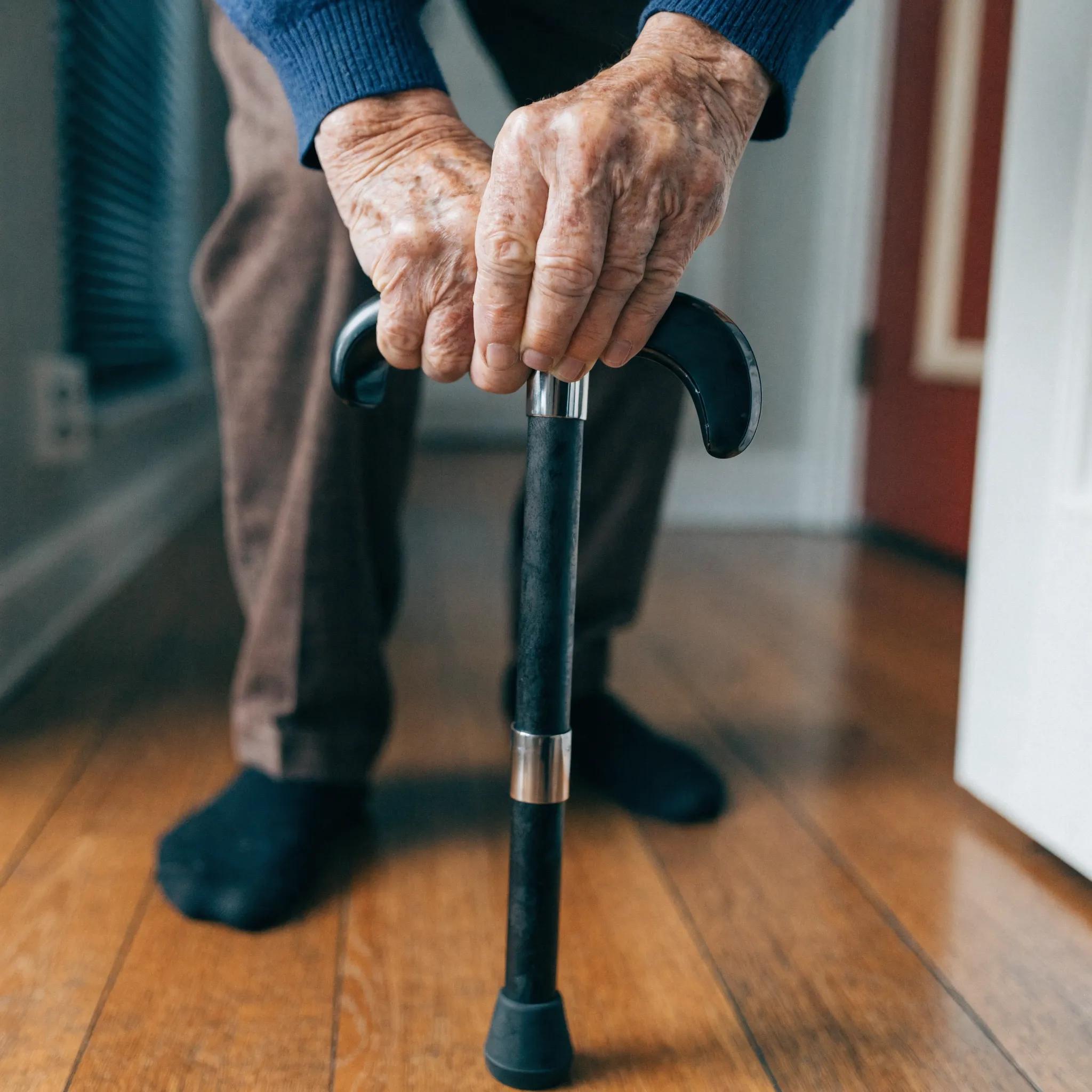 Close-up of elderly hands using a mobility aid, representing physical decline indicators for home care
